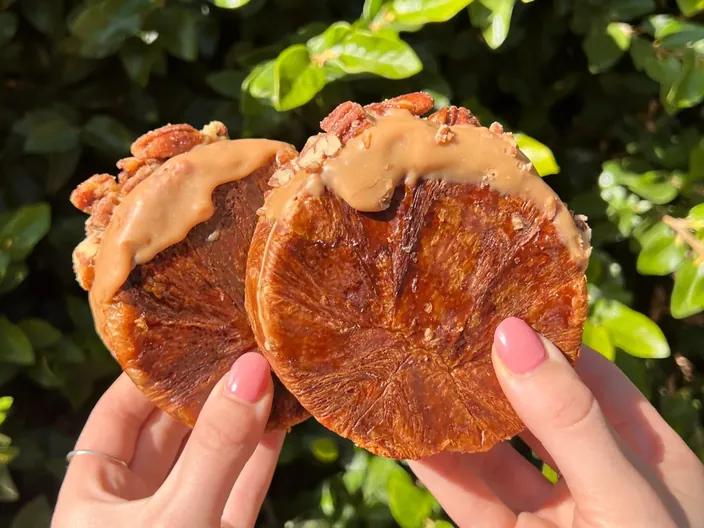 A caramel glazed croissant held up to the light.